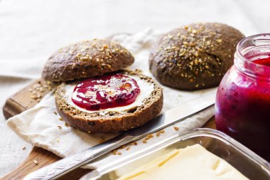 Linseeds, susam ve beyaz haşhaş tohumu ile ev yapımı çavdar ekmeği tereyağı ve ahşap tahta üzerinde Jostaberry reçel ile servis