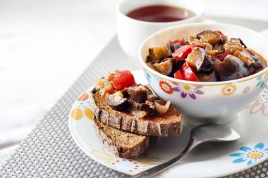 Patlıcan, kırmızı biber ve domates ve kızarmış çavdar ekmeği bir tabakta sebze güveç