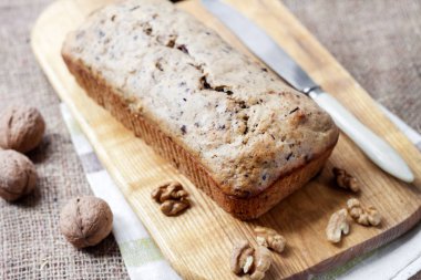 Ceviz ve ahşap kesme tahtası üzerinde koyu çikolata muzlu kek