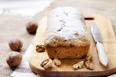 Ceviz ve ahşap kesme tahtası üzerinde koyu çikolata muzlu kek