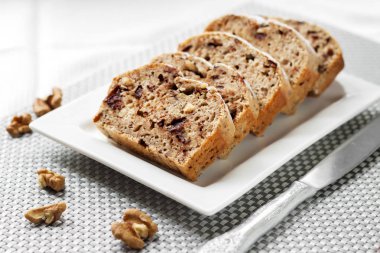 Ceviz ve beyaz bir kare plaka üzerinde koyu çikolata muzlu kek