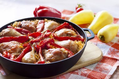 Pirinç ve kırmızı biber dökme demir güveç tavada bir yatak üzerinde pişmiş tavuk uyluk ve bacaklar