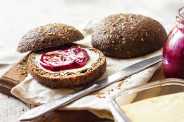 Linseeds, susam ve beyaz haşhaş tohumu ile ev yapımı çavdar ekmeği tereyağı ve ahşap tahta üzerinde Jostaberry reçel ile servis