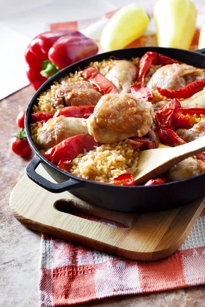 Pirinç ve kırmızı biber dökme demir güveç tavada bir yatak üzerinde pişmiş tavuk uyluk ve bacaklar