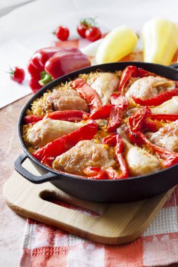 One-pot yemek - tavuk uyluk ve pirinç ve kırmızı biber dökme demir güveç tavada bir yatak üzerinde pişmiş bacaklar