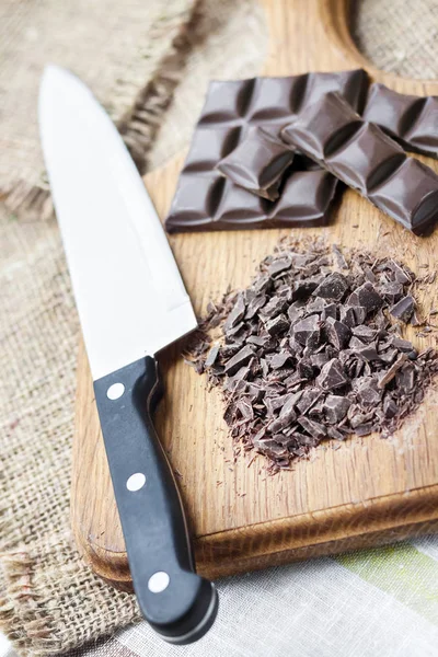 Chopped dark chocolate on wooden cutting board — Stock Photo, Image