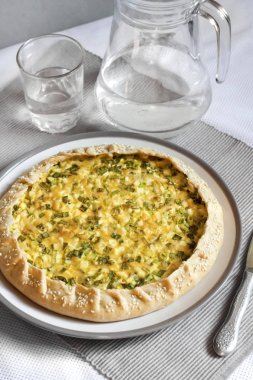 Bir plaka üzerinde yumurta ve yeşil soğan ile tart 