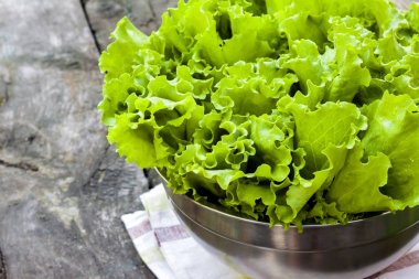 Eski ahşap masa üzerinde metal kase taze marul