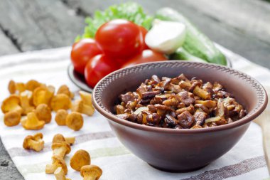 Arka planda salata için taze sebzeler ile rustik kase ve plaka soğan ile Fried chanterelles