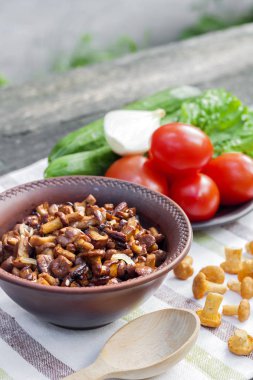 Arka planda salata için taze sebzeler ile rustik kase ve plaka soğan ile Fried chanterelles