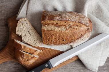 Mutfak masasında ahşap tahta üzerinde dilimleri ile tüm buğday ekmeği Loaf