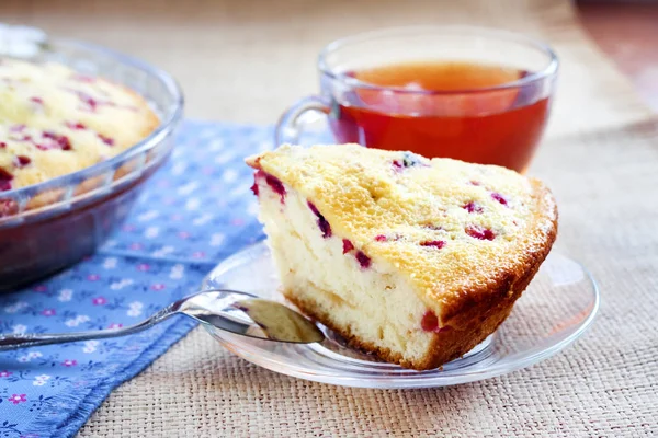 Piece of cowberry pie on glass plate and cup of tea — Stock Photo, Image