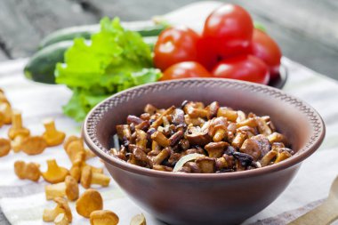 Arka planda salata için taze sebzeler ile rustik kase ve plaka soğan ile Fried chanterelles