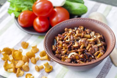 Arka planda salata için taze sebzeler ile rustik kase ve plaka soğan ile Fried chanterelles