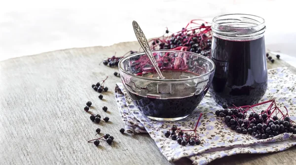 Homemade black elderberry syrup in glass bowl and jar — Stock Photo, Image
