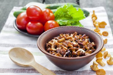 Arka planda salata için taze sebzeler ile rustik kase ve plaka soğan ile Fried chanterelles