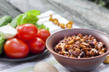 Arka planda salata için taze sebzeler ile rustik kase ve plaka soğan ile Fried chanterelles