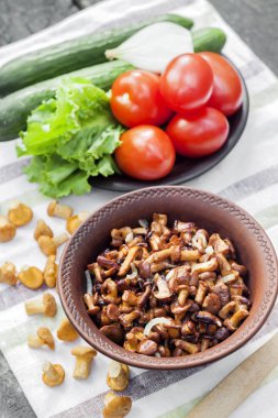 Arka planda salata için taze sebzeler ile rustik kase ve plaka soğan ile Fried chanterelles