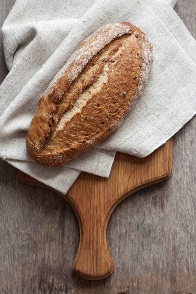 Хліб з цільної пшениці дерев'яна дошка на кухонному столі — стокове фото