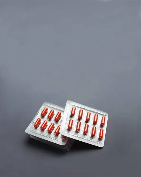 Red pill capsules in blister packs on gray background — Stock Photo, Image