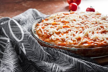 Ev yapımı lazanya ahşap tahtadaki yuvarlak cam fırın tabağında pişirmeye hazır.