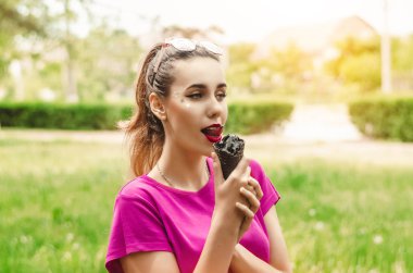 kız siyah dondurma ısırmak istiyormuş. yaz. yakry makiyah ve kırmızı dudaklar. gözleri yıldız. pembe tişört. güneşli bir gün. güneş gözlüğü