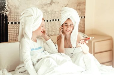 Anne ve kızı. Vücut bakımından sonra rahatlama. Kulaklıkla müzik dinle. Kafaya havlu..