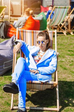 Kız çantanın klozetinde oturuyor. Güneş ışınları. Giysilerin mavi rengi.