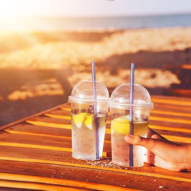 Güneşin ışınları ferahlatıcı buzlu kokteyllerin üzerine düşer. Arka planda deniz. gün batımı