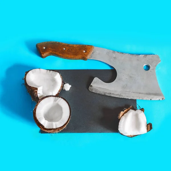 coconut on a blue background. black template for recording. a sharp ax near the coconut. food