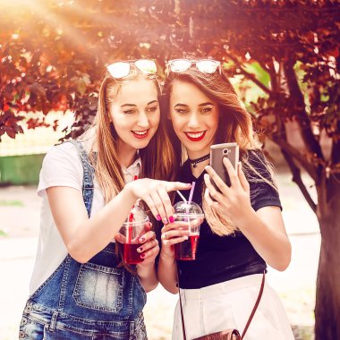 Kızlar telefonda bir şey izliyorlar. Kablosuz internet ve haberler. Yazın kokteyl..