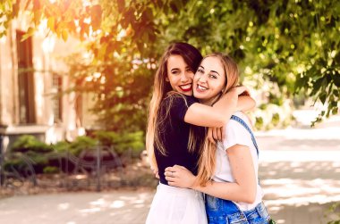 Kızlar sarılır. Mutlu bir gülümseme Kırmızı ruj. güneş gözlüğü.