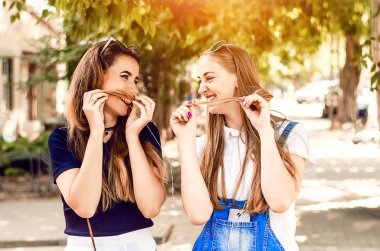 İki mutlu kız arkadaş birbirlerine bakıp gülümsüyor.