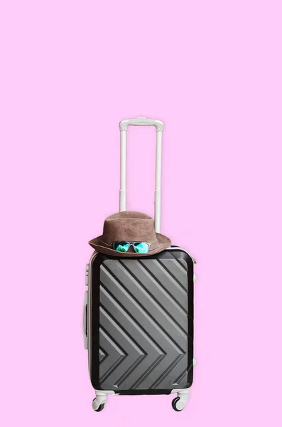 用轮子旅行的手提箱 帽子和眼镜粉色背景 — 图库照片