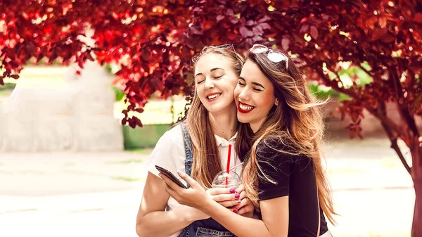 Yüzünde bir gülümsemeyle mutlu iki kız arkadaş sarılıyor.