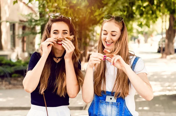 İki kız arkadaş şımarır. Mutlu kız arkadaşlar yürüyor.