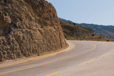 Güneşli bir günde, Beyaz Dağlar 'daki Omalos köyünün yakınındaki Girit adasındaki bir dağın etrafından dolanan yol bölümü.