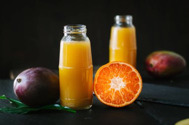 Taze detoks mango ve portakallı smoothie ile dolu cam şişeler..