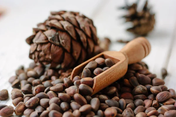 Pine nuts in wooden spoon on a heap of pine nuts