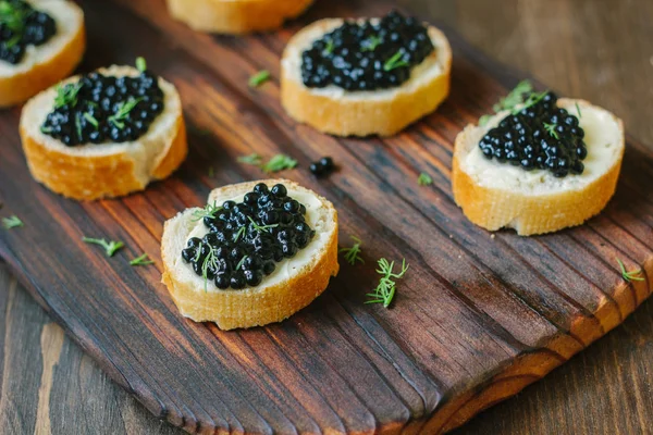 Ahşap mutfak kartı ekmek parçaları üzerinde siyah havyar