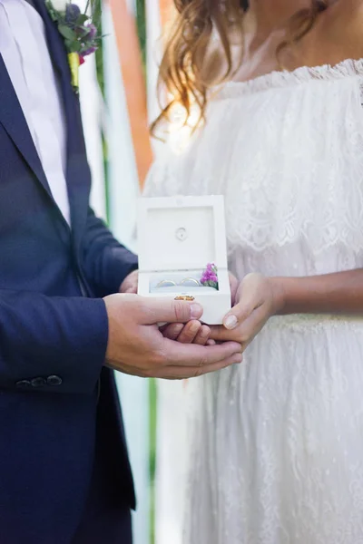 Box with wedding rings in groom and bride hands