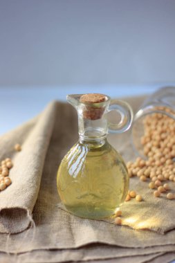 Etrafında soya fasulyesi olan cam şişedeki soya fasulyesi yağı.