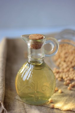 Etrafında soya fasulyesi olan cam şişedeki soya fasulyesi yağı.