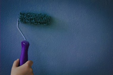 Duvarın üzerinden boya silindiri, koyu mavi boyayla boyanmış.