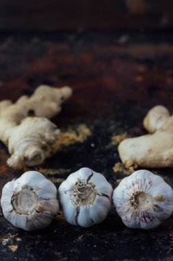 Siyah kırsal yüzeyde zencefil kökü ve sarımsak..
