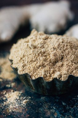 Siyah kırsal yüzey üzerinde metal kâse üzerinde zencefil baharatı..