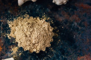 Siyah kırsal yüzey üzerinde metal kâse üzerinde zencefil baharatı..