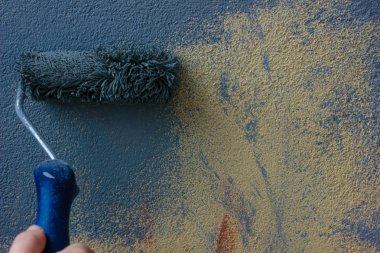 Sarı duvarın üzerinde mavi renkte boya var.