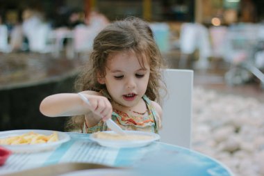 Küçük kız fast food restoranında yemek yiyor..