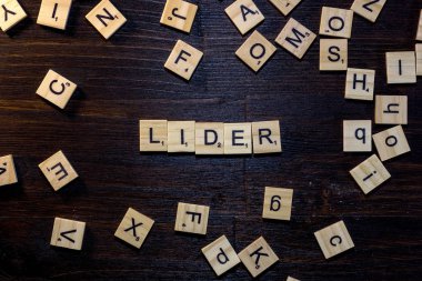 Lider kelime ile yapılan scrabble harf üzerinde siyah bir ahşap masa.